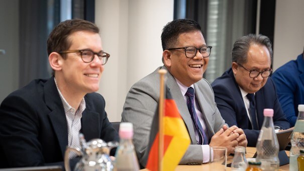 Ben Brake und Ichwan Nasution sitzen nebeneinander und schauen lächelnd nach vorne